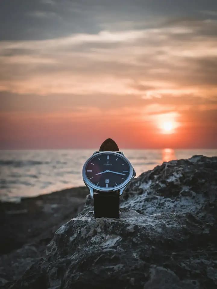 Relógio sobre uma pedra ao pôr do sol